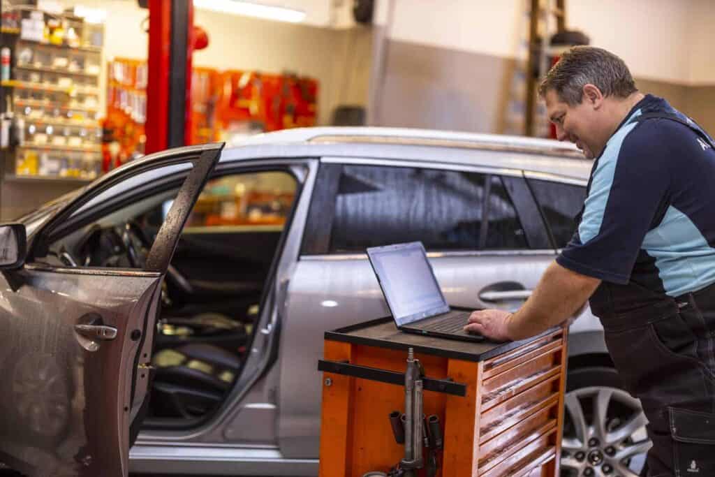 Mekaniker tjek bilen imens han er på computeren